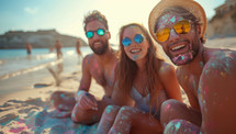 Three friends covered in colorful powder at the beach
