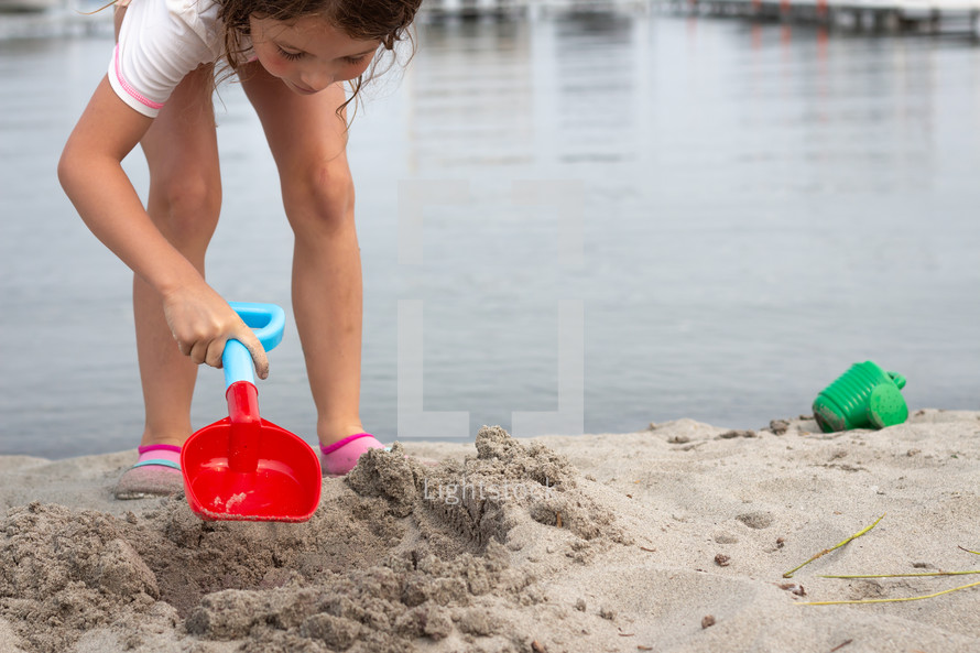 a girl playing in sand on a beach 