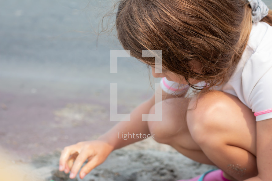 a girl playing in sand on a beach 