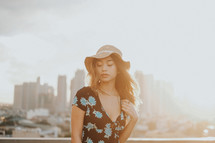 a young woman in a sundress and sunhat in a city 