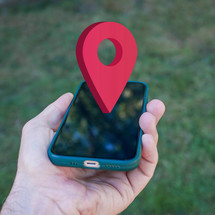 hand holding a smart phone with a location symbol