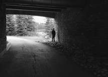 an iPhone capture of a man's silhouette under a dark bridge