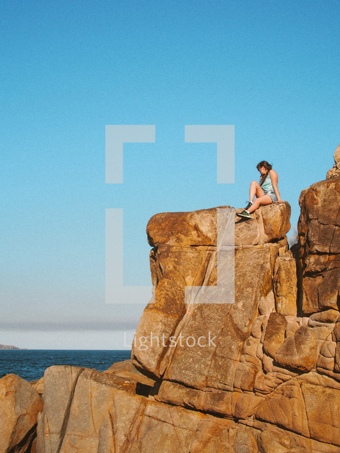 woman sitting on a cliff overlooking a Bay