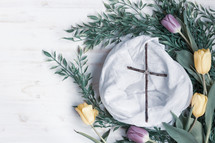 cross on white linen surrounded by tulips 