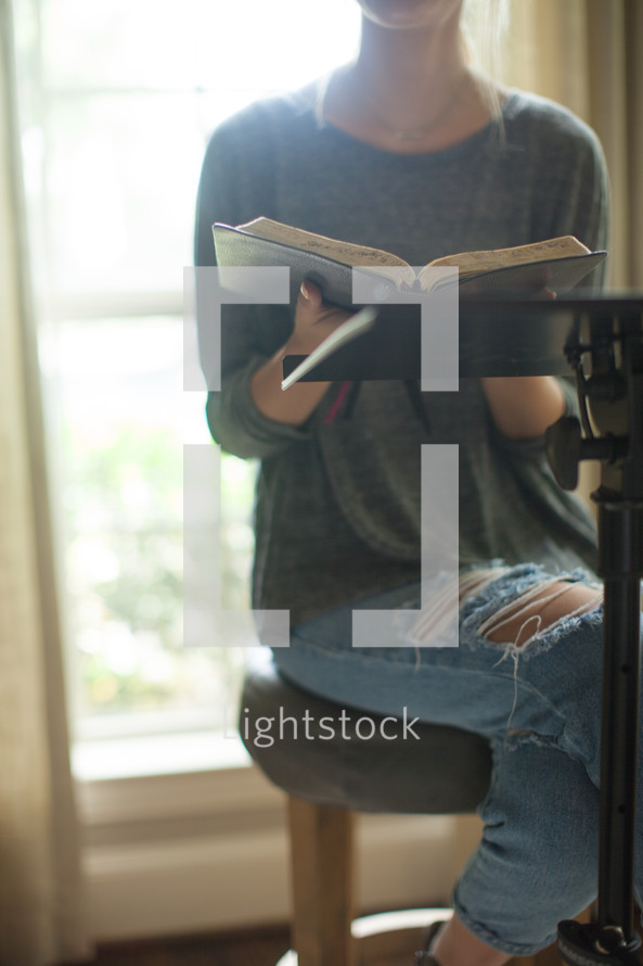 A woman sitting at a podium with a Bible.