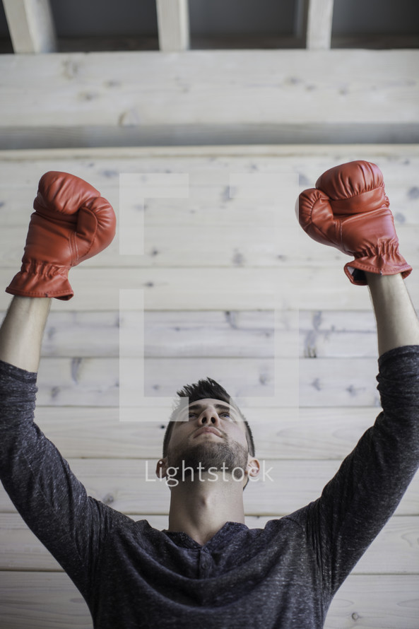 man wearing boxing gloves with raised arms