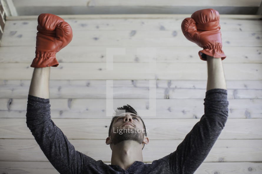 man wearing boxing gloves with raised hands 