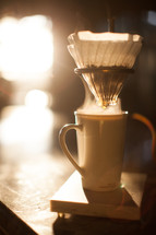 slow brew coffee filter and coffee mug in morning sunlight 