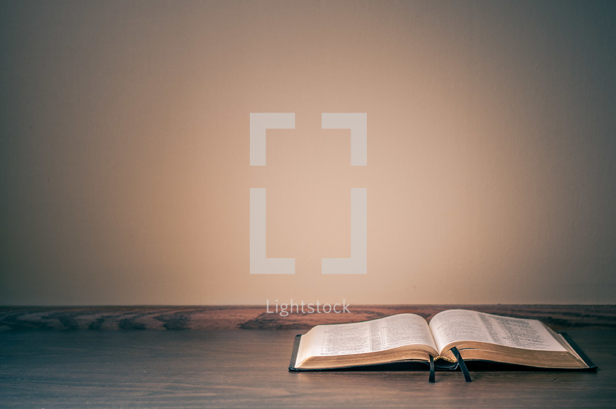 Open bible on a table against a wall