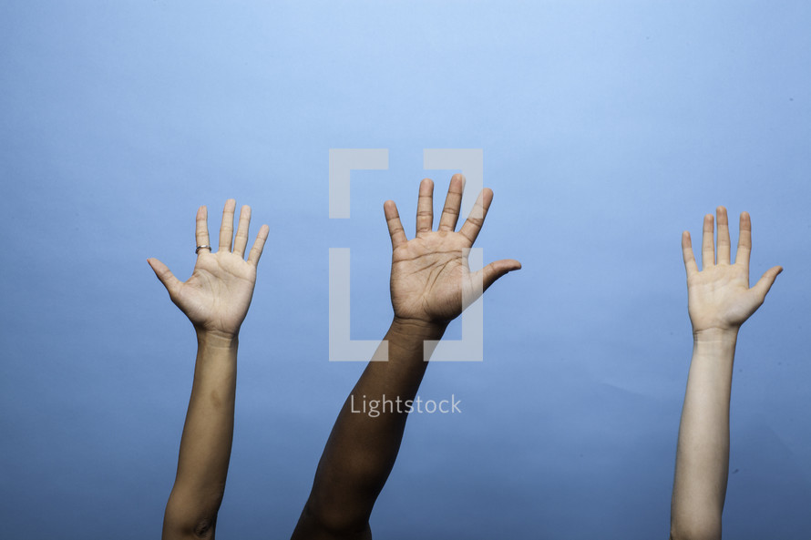 raised hands against a blue sky 