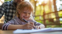 Smiling Child Drawing with Pen on Paper Outdoors with Father