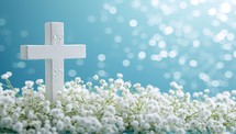 Cross with white gypsophila flowers on blue bokeh background