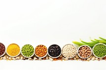 Different kinds of beans in bowls on white background with copy space.