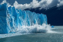 Glacier Calving with Ice Crashing into Lake with Mountains in Background