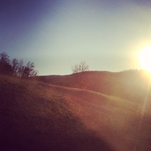 sunburst over rolling hills