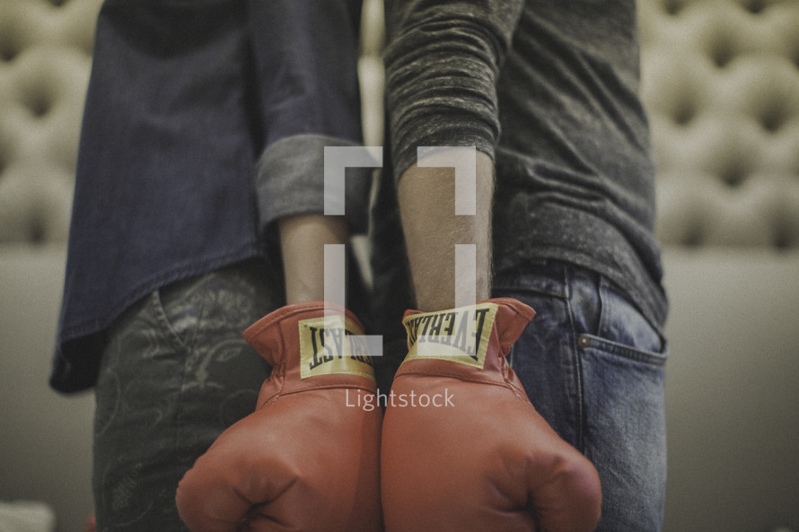 couple standing back to back wearing boxing gloves 