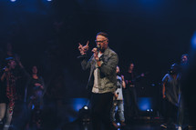 worship leader speaking and singing to a congregation 