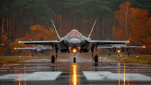 Fighter jet ready for takeoff on rainy runway surrounded by autumn trees