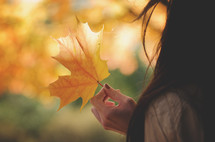 teen girl holding a fall leaf 