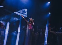 worship leader speaking and singing to a congregation 