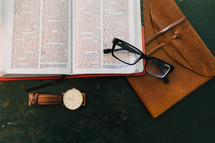 pen on a Bible, watch, coffee cup, reading glasses, journal