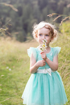 a girl child holding picked flowers 