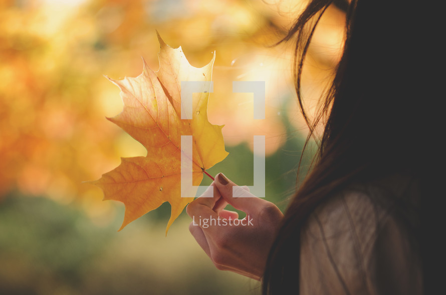 teen girl holding a fall leaf 