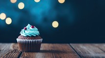Cupcake with blue cream on a wooden table in front of bokeh background