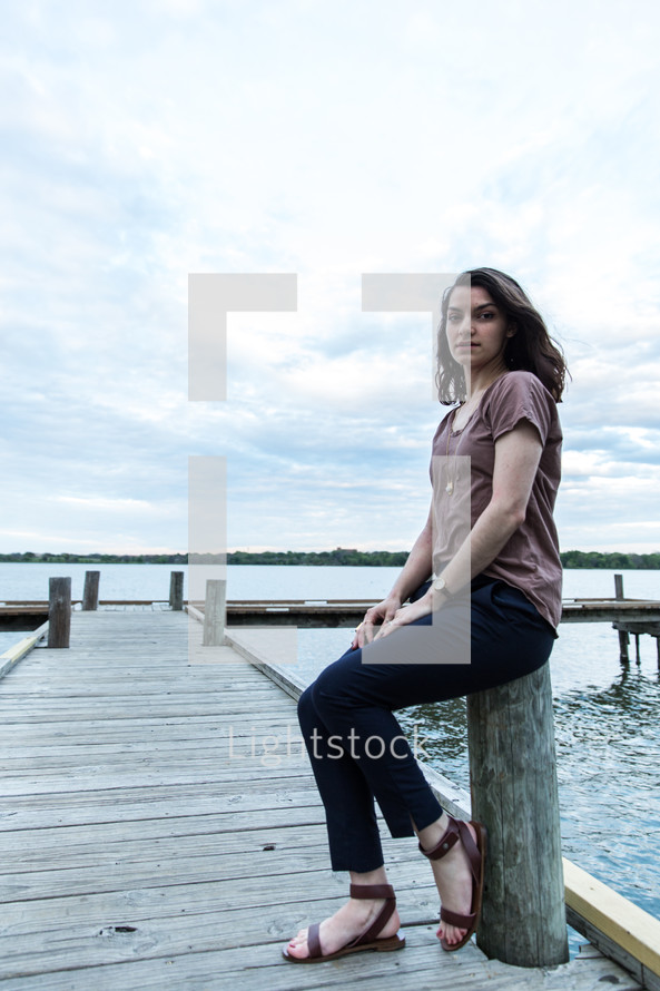 teen girl sitting on a wooden pier 