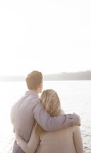 couple standing together in front of a lake 