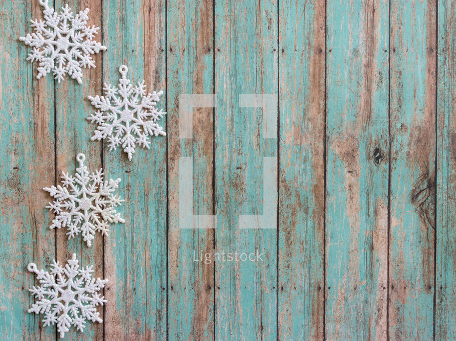 snowflake ornaments on a green wood background 
