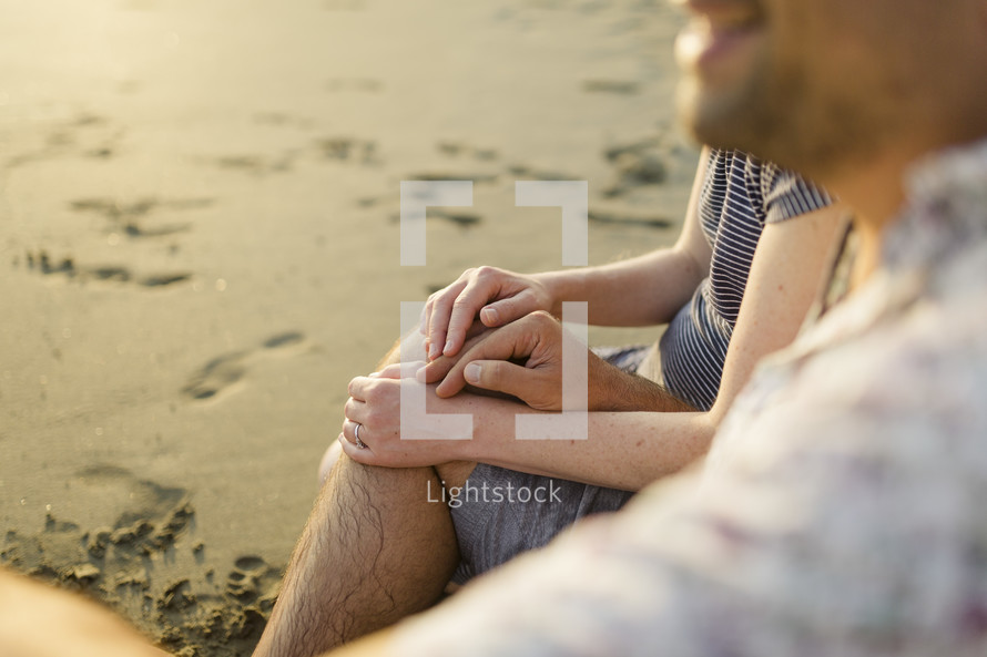 Close up of a husband and wife's hands on a beach. 
