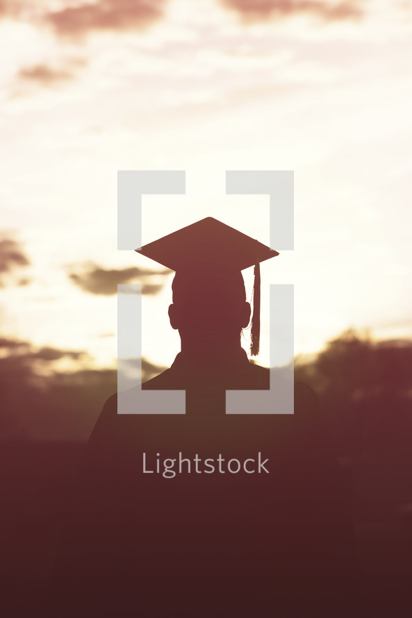 silhouettes of graduate in cap and gown.