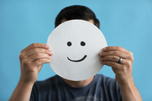 a man holding up a smiley face 