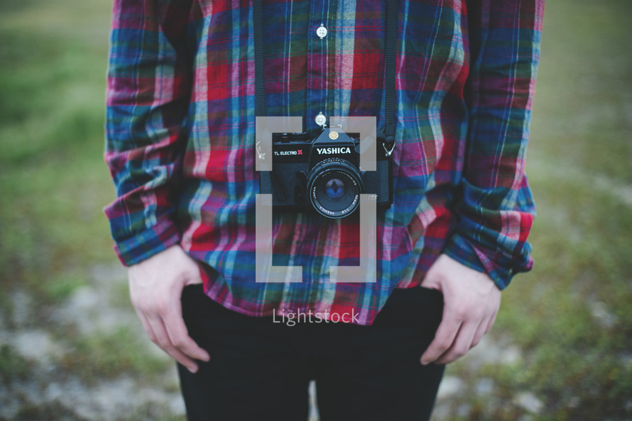 man in a plaid shirt and camera around his neck 