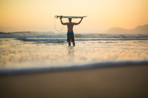 man holding his surfboard over his head checking out the waves