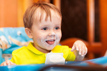 Happy child dirty with cream yogurt