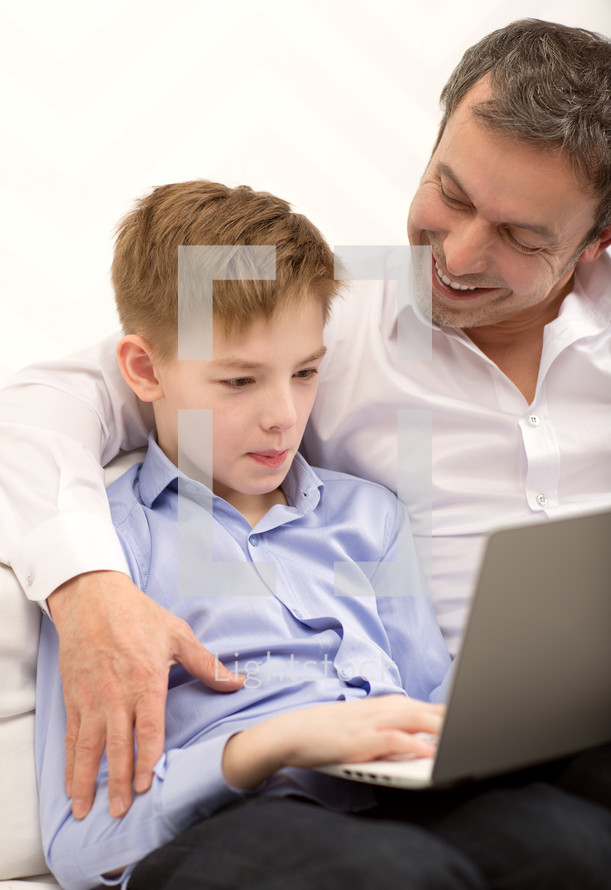 Father watching son working with laptop