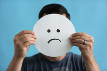 a man holding up a frown face 