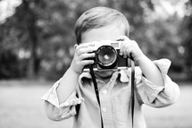 A little boy photographs the photographer with a vintage toy camera.