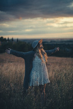 a woman with outstretched arms standing in a field 