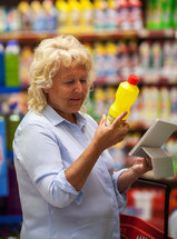 Senior woman with pad reading the detergent label