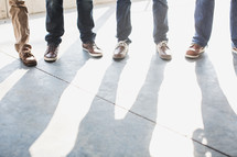 feet of men standing on a sidewalk 