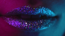Fashion model with bright shiny sparkles on plump lips. Macro view of woman with glamorous make-up. Nightlife, night club concept.