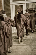 rows of graduates walking into a ceremony 