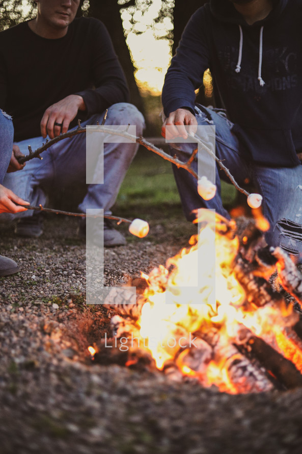 men roasting marshmallows around a fire 