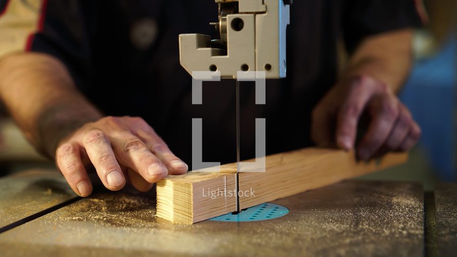 Handwork, carpentry concept, woodworking. Carpenter working in in factory atelier. Joiner labourer cuts wooden plank on jigsaw machine.
