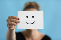 a woman holding up a smiley face 