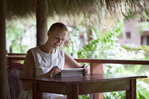 Smiling woman using tablet computer in cafe during vacation