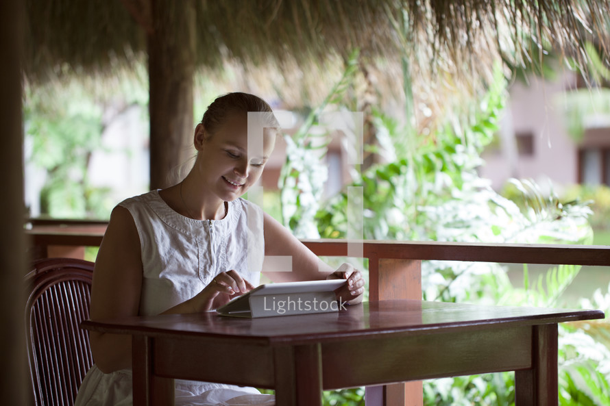 Smiling woman using tablet computer in cafe during vacation